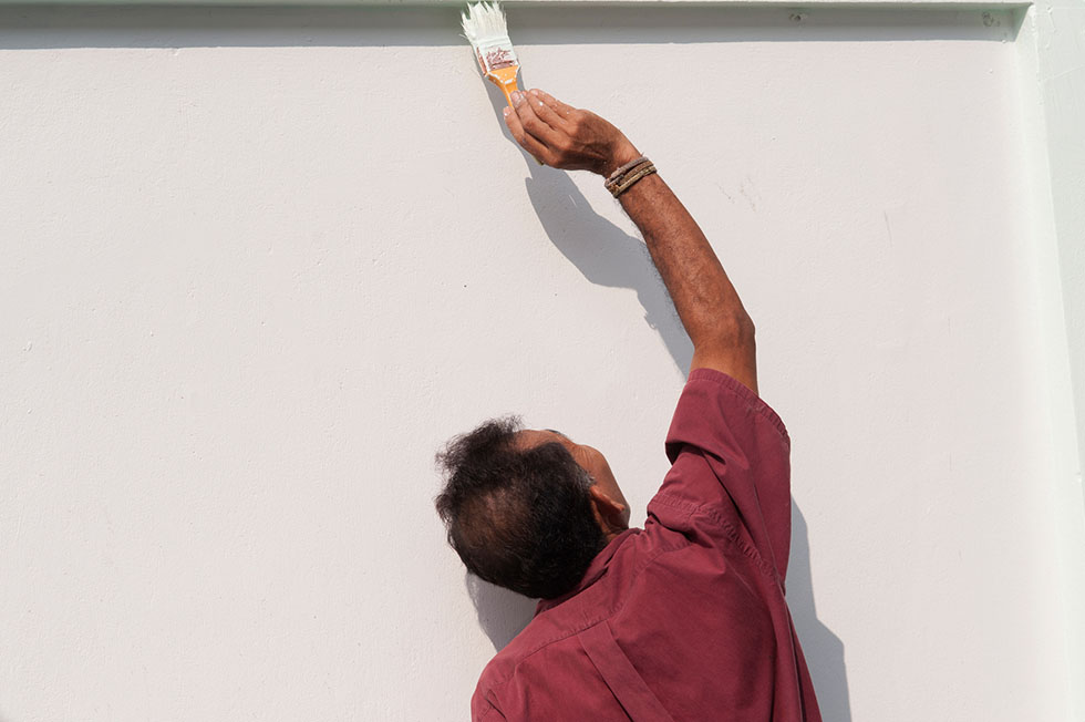 Male work painting the white wall.