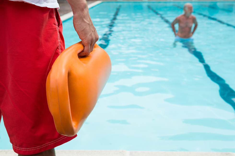 Lifeguard holding rescue buoy at poolside